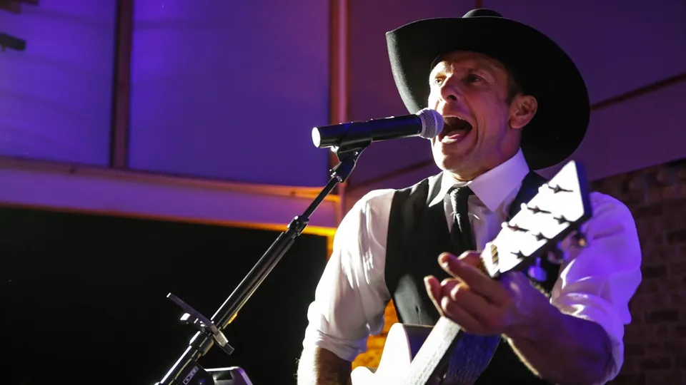 A singer in a cowboy hat performing at Brady and McKenzie's Barr Mansion reception