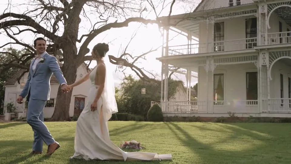 Suana and Nick walking across the lawn in front of Barr Mansion
