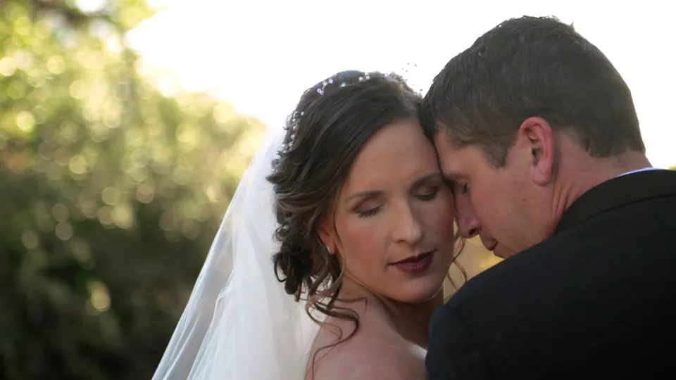 A bride and groom touching foreheads in soft sunlight at Pecan Springs Ranch