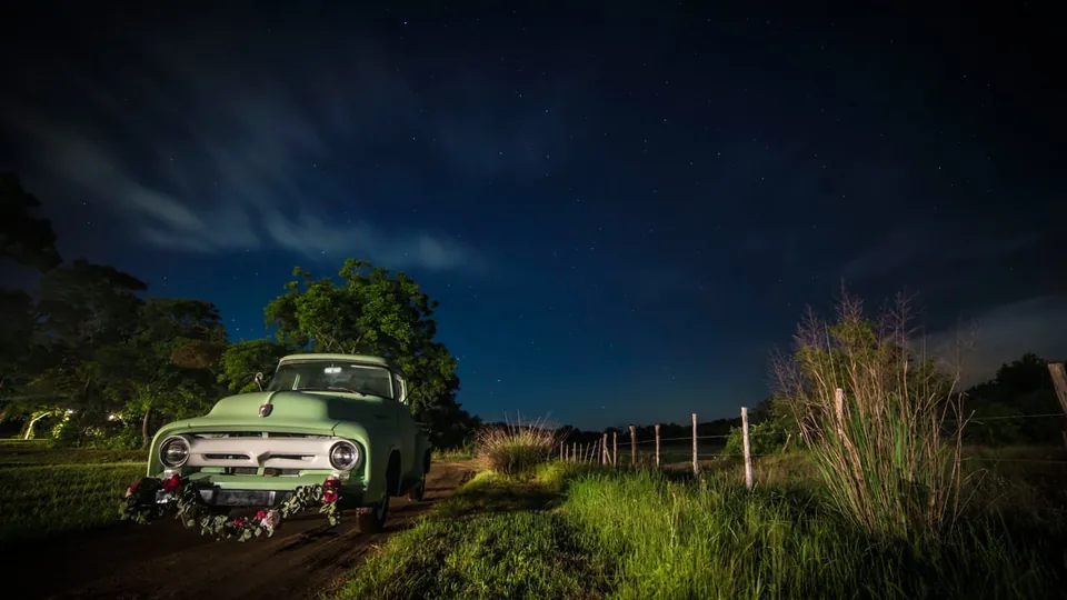 A vintage green truck under a night sky at Pecan Springs Ranch, a still from Adam Grumbo's film of Paige and Matt's wedding
